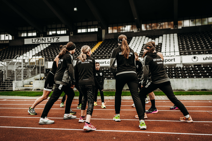 Kinder und Jugendliche beim Triathlontraining dehnen sich auf Laufbahn